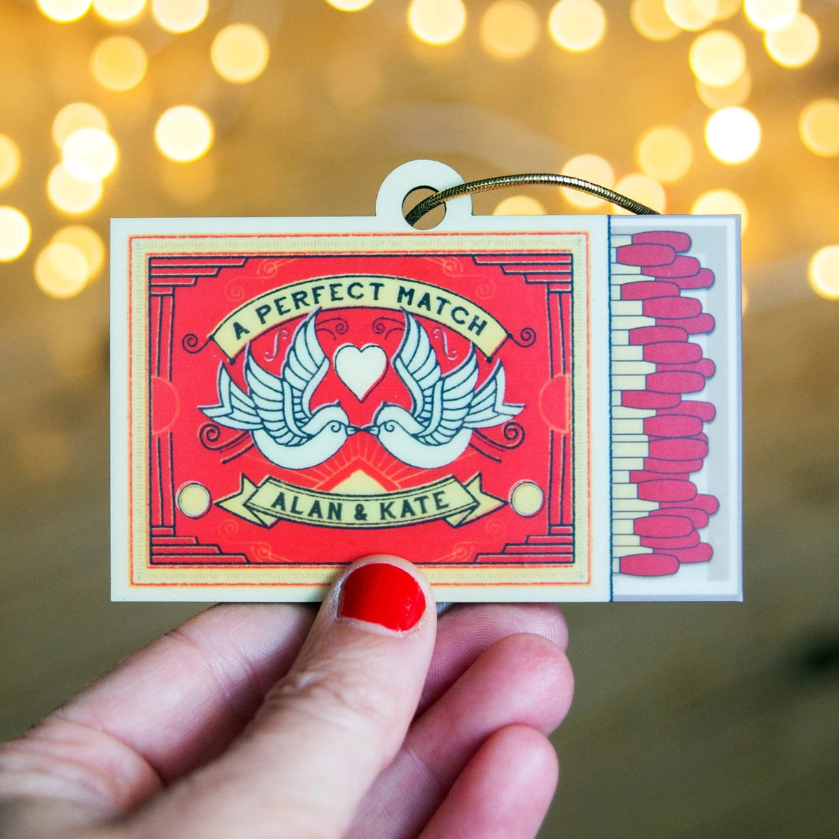 Matchbox with 'A Perfect Match Alan & Kate' text against a blurred bokeh background