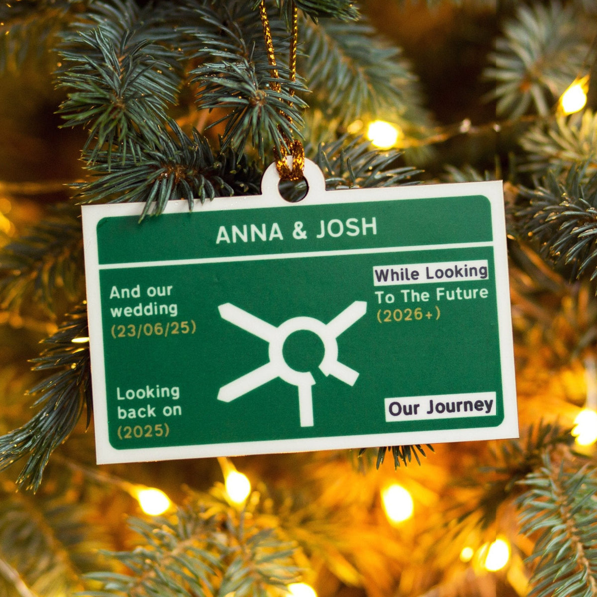 Personalised Christmas tree bauble on a tree with 'ANNA & JOSH' and road sign design.