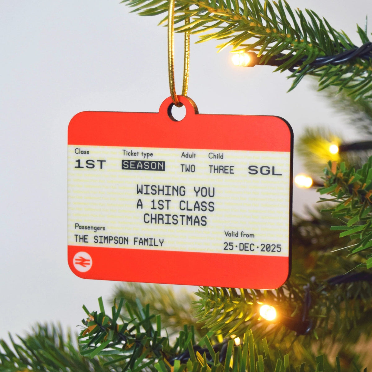 Christmas ornament with a train ticket design hanging on a tree.