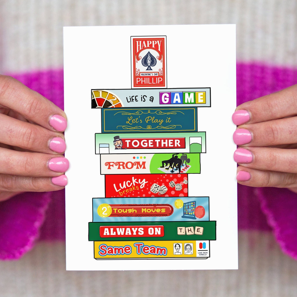 Colourful card with text and board game illustrations held by hands against a textured background