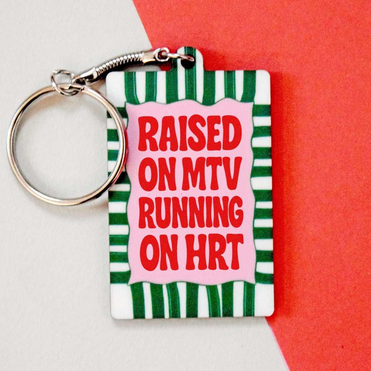 Keychain with 'Raised on MTV Running on HRT' text on a striped background
