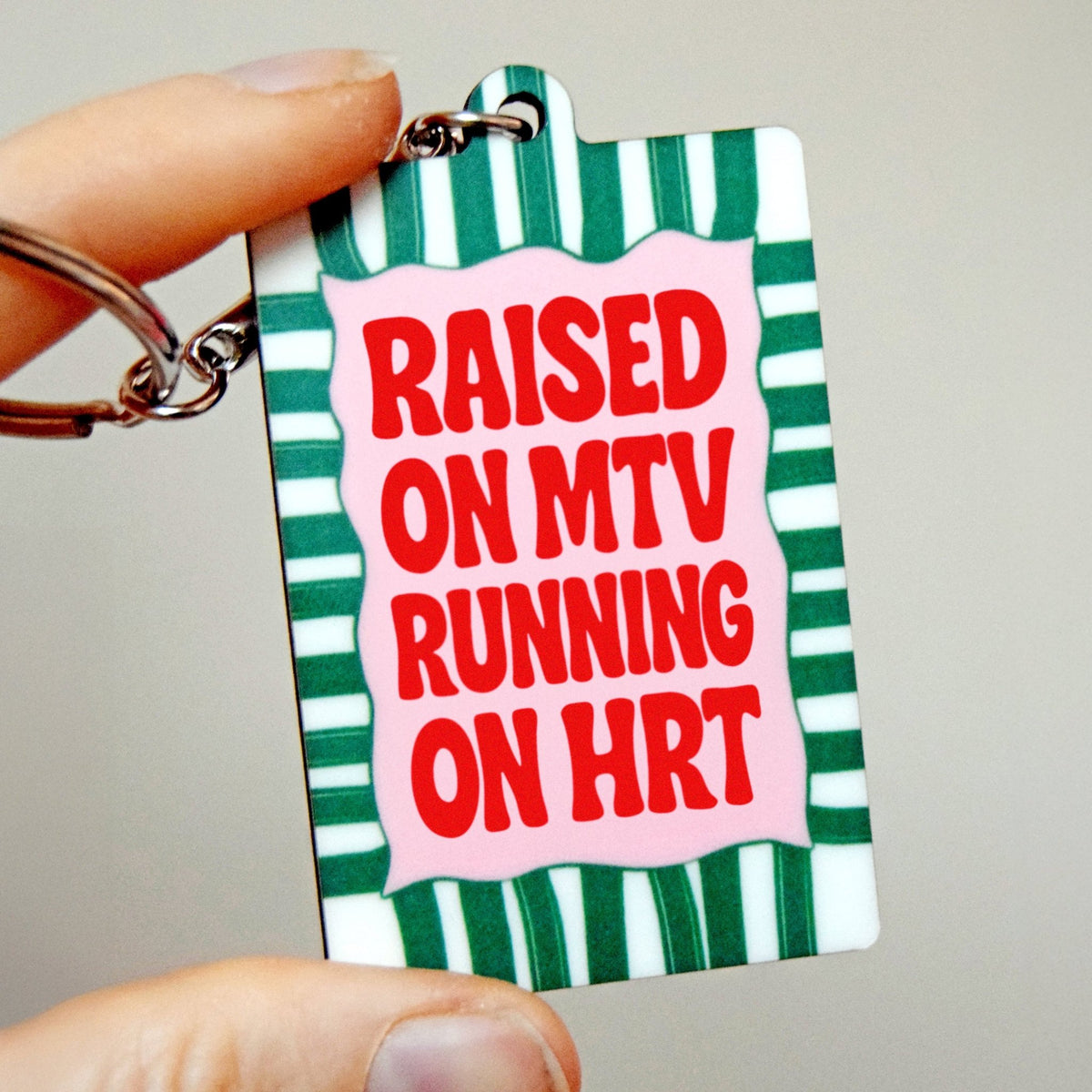Keychain with 'Raised on MTV Running on HRT' text on a green and white striped background