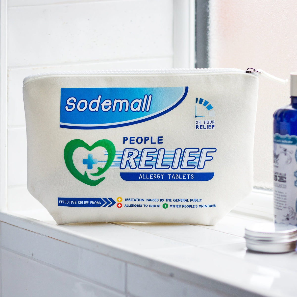 A white Sodemall People Relief Allergy Tablets pouch sits on a white tiled windowsill, with a blue bottle and a small silver tin nearby.