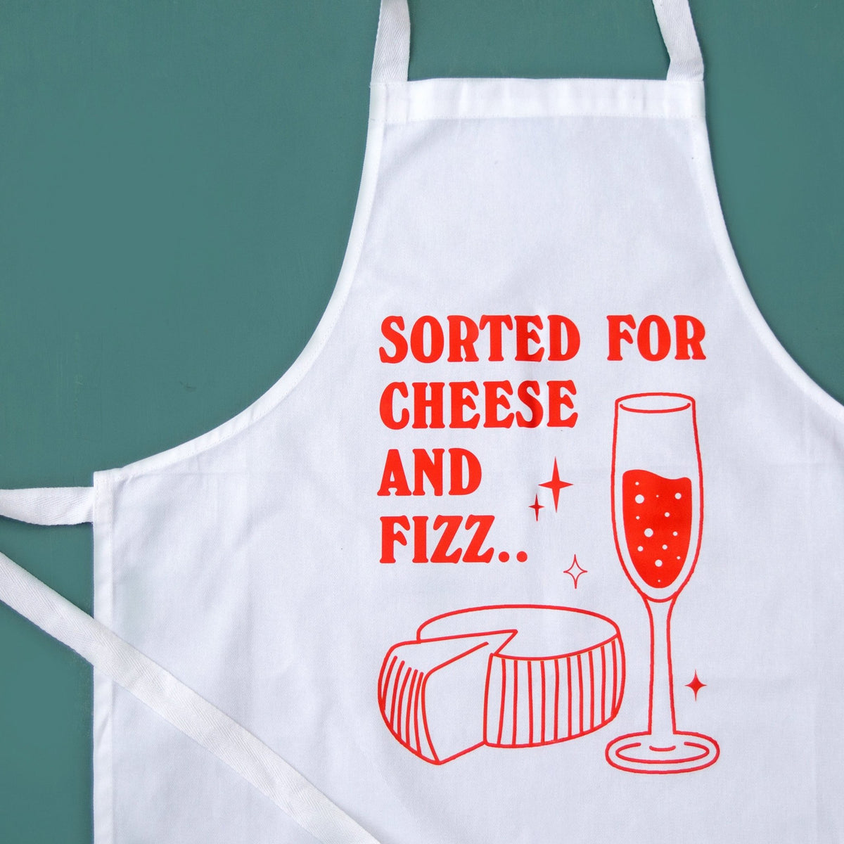 A white apron with red printed text reading 'SORTED FOR CHEESE AND FIZZ.