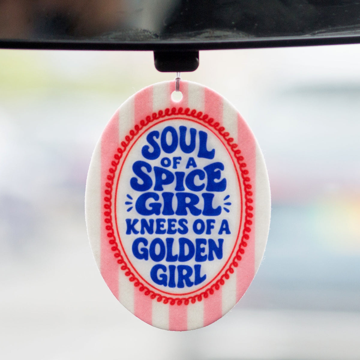 Round air freshener with text 'Soul of a Spice Girl, Knees of a Golden Girl' on a blurred background