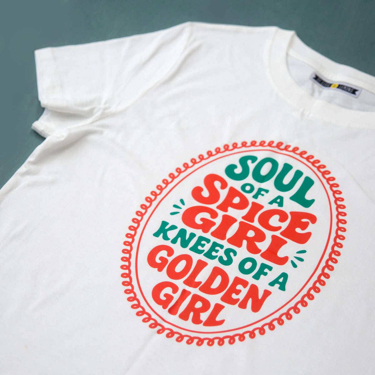 White t-shirt with colorful text design on a gray background