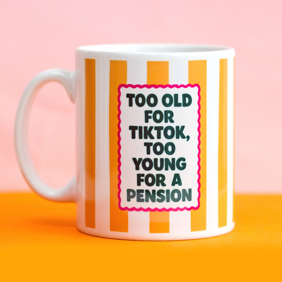 Mug with striped design and humorous text on a pink and orange background