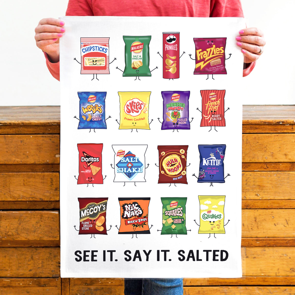 a white cotton tea towel featuring fun illustrations of a number of the nations favourite crisp packets