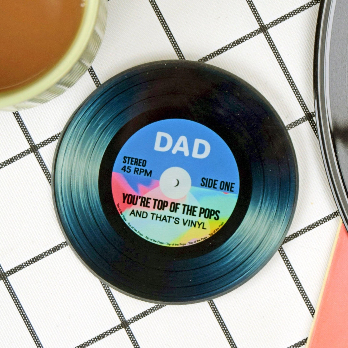Small vinyl record with a colorful label on a checkered surface
