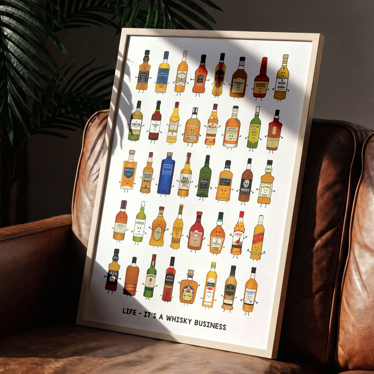 Framed poster with illustrations of whiskey bottles on a wall next to a brown leather couch.