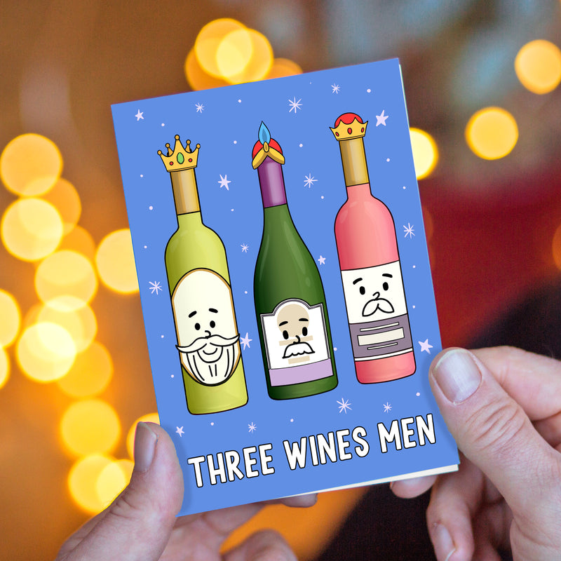 Christmas card with cartoon wine bottles labeled 'Three Wines Men' held against a blurred festive background.