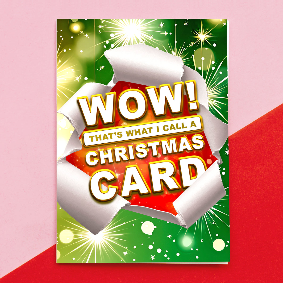 A Christmas card shown standing upright against a pink and red background. The card features a green and red festive design with white torn-paper effects and large text reading “WOW! THAT'S WHAT I CALL A CHRISTMAS CARD.