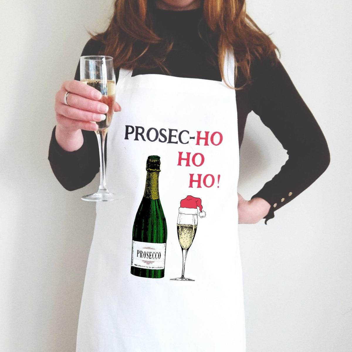 Person wearing a white apron with Prosecco-themed design, holding a glass of champagne.